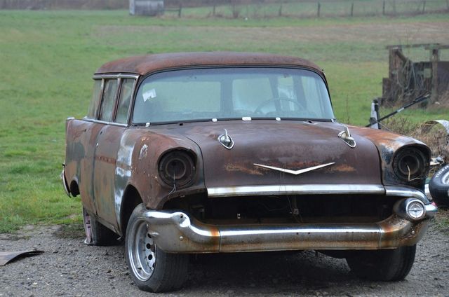 Rusted 1950s station wagon with its chrome bumper, parked in grass